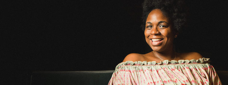 Gabrielle Randle-Bent sits in a dark theatre and smiles.