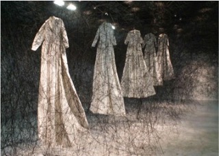 A series of hanging, white dresses with black threads criss-crossing over them, creating a web.