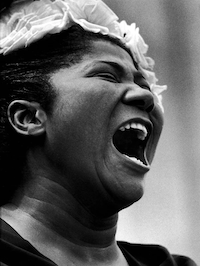 A woman sings passionately. Her mouth is open and her eyes are closed, and she looks fierce and powerful.