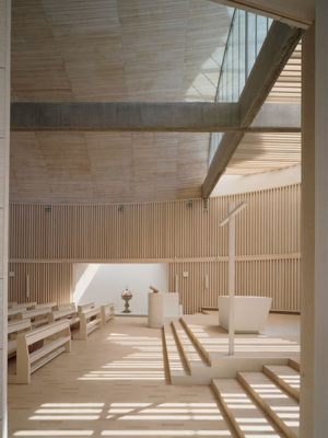 A church with lots of light wooden, curved beams.