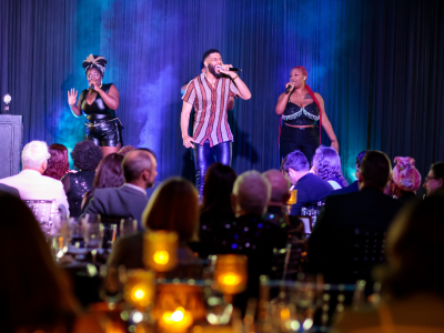 A man sings onstage flanked by backup singers.