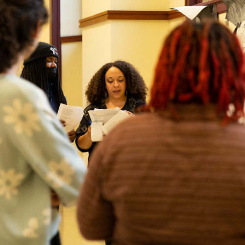 A person reads from a script in a crowd of people.