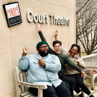 Three people sitting outside a building making silly faces and pointing to a sign that says Court Theatre.