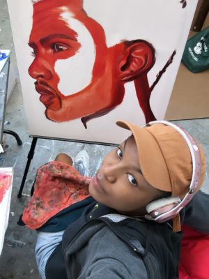 A person sits in front of a partially-completed painting.
