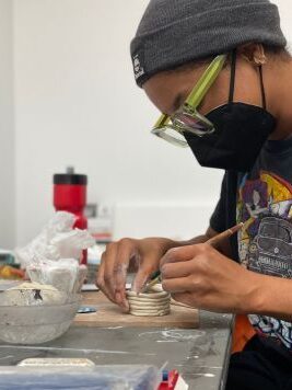 A person builds a pot out of clay.