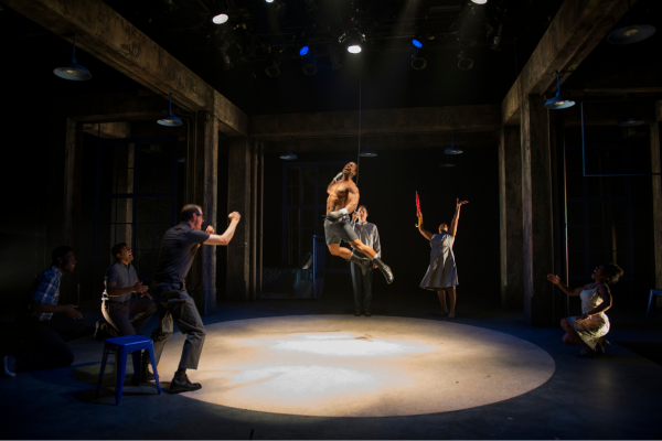 A man jumps center stage while a cheering crowd looks on.