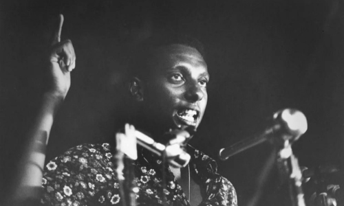 A man points his finger to the sky while addressing a crowd.