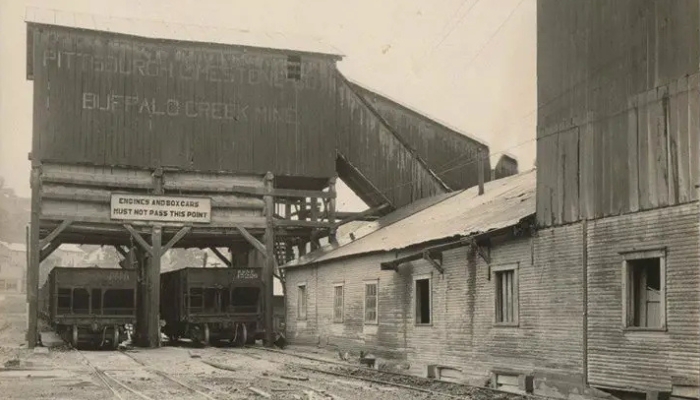 Dilapidated railway tracks lead to two railway cars in the distance. Above them, a building labeled: PITTSBURGH LIMESTONE/BUFFALO CREEK MINE.