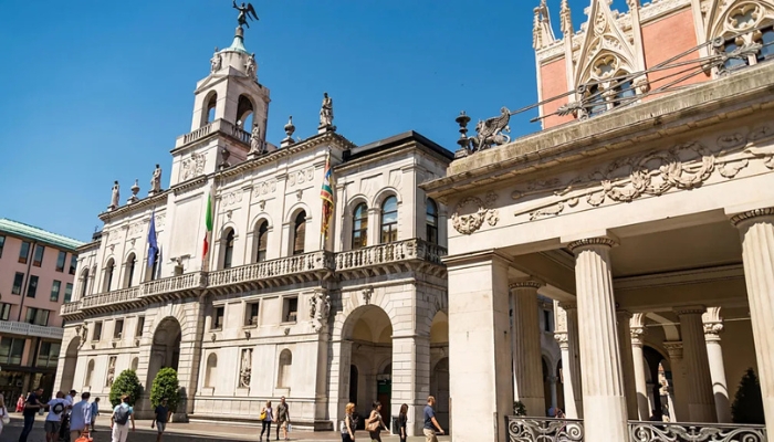 An image of a building with large stone columns, decorative stone details, archways, and a tower.