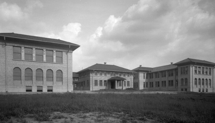 A complex of multiple brick buildings, photographed in black and white.