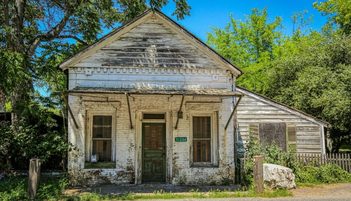 A brick house in disrepair, in need of repairs and a fresh coat of paint.